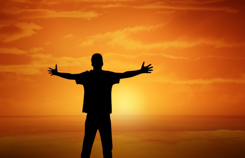 Man shows his strengths with open arms facing the sunset.