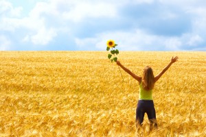 Girl standing in a field holding a sunflower showing how important it is to know yourself.