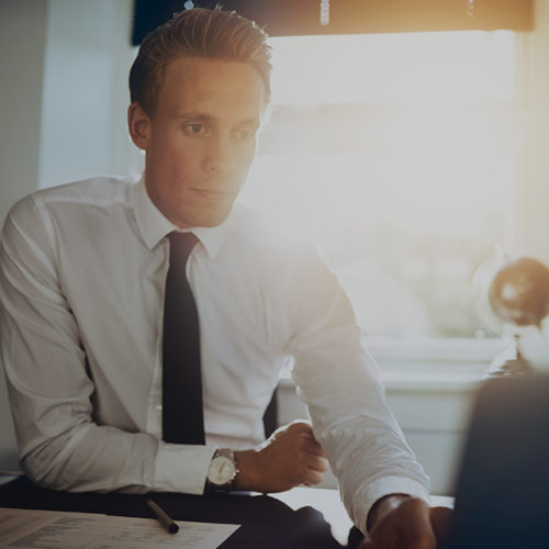Professional business leader working at his desk with the sun behind him.