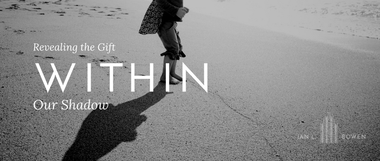 Revealing the gift within our shadow header with kid standing on the sand and he shadow on the ground.